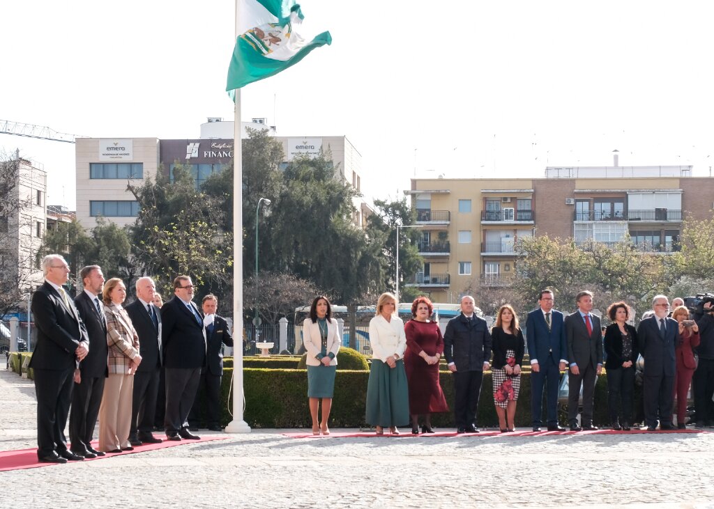 La bandera de Andaluca ondea al viento tras ser izada en presencia de antiguos presidentes del Parlamento, a la izquierda, y la actual presidenta, Marta Bosquet, junto a los miembros de la Mesa del Parlamento a la derecha 