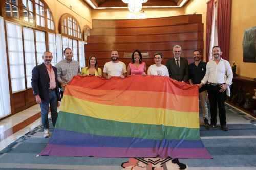  La presidenta del Parlamento, Marta Bosquet, representantes de la Red Estatal de Municipios Orgullosos y otras personalidades portan la bandera de 