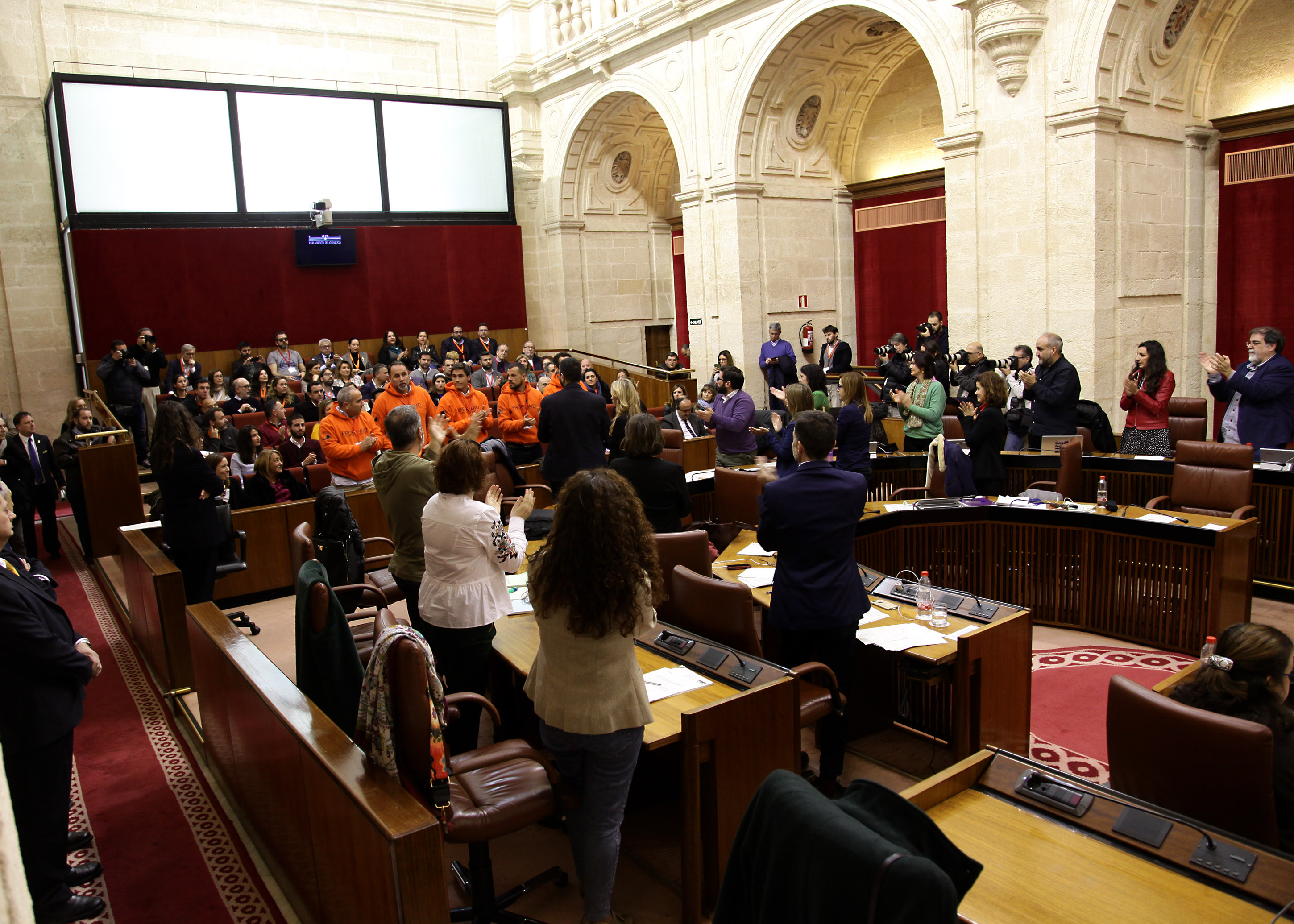 El Pleno de Parlamento puesto en pi� aplaude a los compa�eros de los bomberos de la ONG Proemaid tras la lectura de la Declaraci�n Institucional