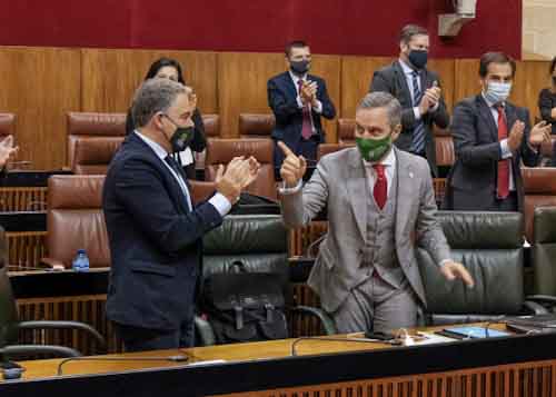 Juan Bravo, consejero de Hacienda, hace un simptico gesto al consejero de la Presidencia, Elas Bendodo 