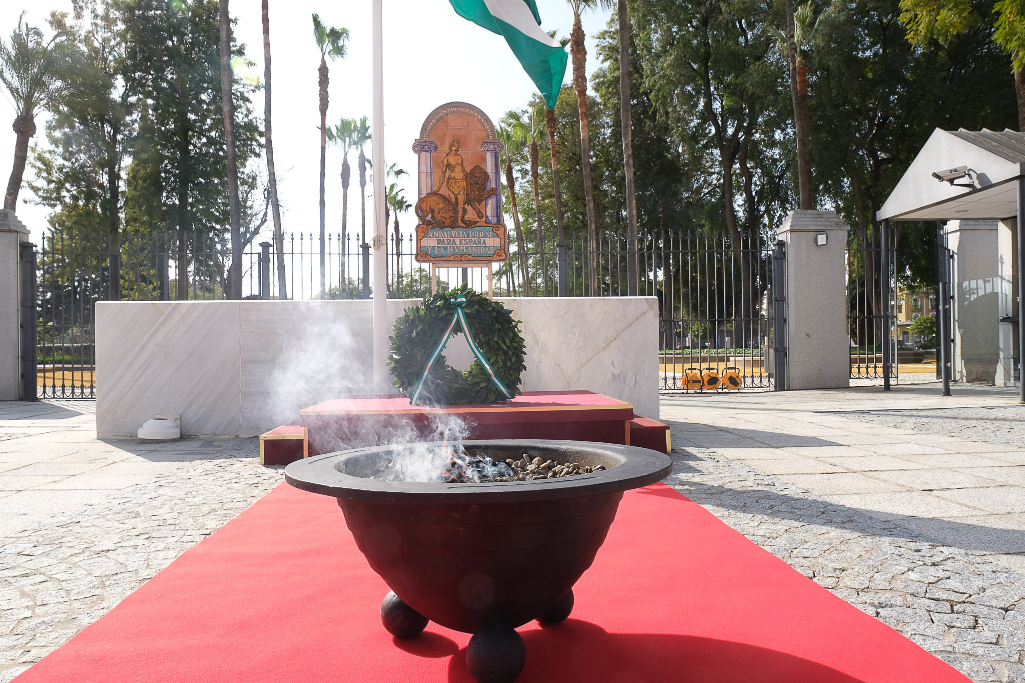 La bandera andaluza ondea sobre la r�plica del escudo de la casa de Blas Infante, la corona de laurel en homenaje a las v�ctimas de la COVID-19, y la llama encendida del pebetero en los actos del D�a de Andaluc�a  